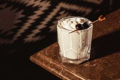 a glass filled with whipped cream and black olives