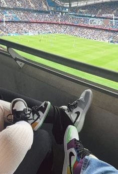 two people sitting in the bleachers at a soccer game with their feet up