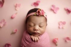 a newborn baby is wrapped in a pink blanket and sleeping with her head on her hands