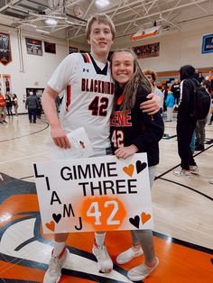 two young people standing next to each other holding a sign