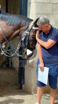 a man standing next to a horse with his face close to it's bridle