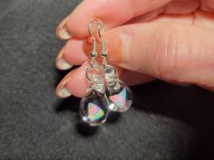 "Make a splash with these Mermaid's Tears earrings!  These gorgeous hand-blown teardrop earrings are made with only the highest quality borosilicate glass and features a mesmerizing Gilson opal polished nugget that shimmers with blue, green, yellow, and even a hint of red within the opal encased in glass. These earrings come mounted on sturdy sterling silver fish hooks, perfect for those with sensitive ears. And with a heavy gauge sterling that won't bend out of shape, you can wear these earrings with confidence knowing they'll stay securely in place. Measuring .85\" x .5\", these earrings dangle 1.5\" for a perfect statement for those who love unique jewelry.   Plus, with a gift box included, they're ready for gift giving or treating yourself to a special accessory. Don't forget to look a Nickel-free Glass Drop Jewelry, Nickel-free Teardrop Glass Jewelry, Nickel-free Glass Teardrop Jewelry, Glass Drop Earrings With Matching Set, Hypoallergenic Teardrop Glass Jewelry, Teardrop Glass Beads For Jewelry Making, Glass Teardrop Jewelry With Matching Earrings, Glass Drop Earrings As Gift, Iridescent Sterling Silver Dangle Earrings