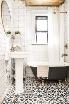 a bathroom with a black and white bathtub next to a sink under a window