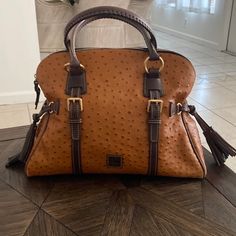 Dooney & Bourke Large Brown Ostrich Domed Satchel Great, Gently Owned Condition. Clean Interior, Light Wear On Edges In The Bottom But It’s In Truly Amazing Condition! (See Pics) Zipper Closure Strap Drop Length: 8" H 12" X W 6.5" X L 15" One Outside Pocket. One Inside Zip Pocket. Two Inside Pockets Cell Phone Pocket Inside Key Hook Red Cloth Lined Gold Tone Hardware And Feet Dooney Bourke Ostrich Handbags, Key Hook, Key Hooks, Dooney & Bourke Bags, Dooney Bourke, Inside Pocket, Zip Pockets, Satchel, Cell Phone