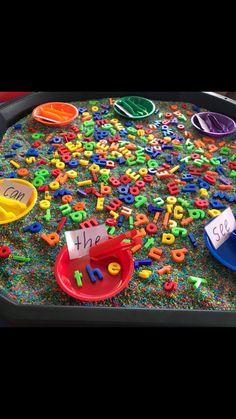 a tray filled with letters and numbers on top of a table next to a sign that says learning through play