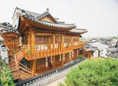 a wooden building with many windows and balconies on the top floor is surrounded by greenery