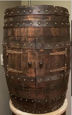 an old wooden barrel with metal rivets on the top and bottom, sitting on a pedestal