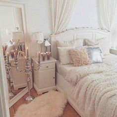 a bedroom with white bedding and candles on the nightstands in front of it