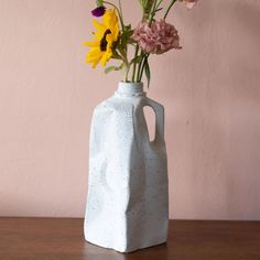 a vase with flowers in it sitting on a table next to a pink wall,