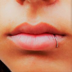 a woman's nose with a ring on the tip of her lip in front of her face