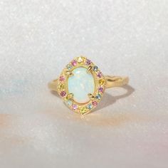 One of a kind 14k Yellow Gold Australian Opal Ring, enraptured by a dreamy pastel halo of Aquamarine, Pink Sapphires and Yellow Sapphires. 💌 Please write desired size (between 4-8) in *Notes* section at checkout Opal enhances cosmic consciousness and imparts mystical visions. Acting as a mirror, it reflects your thoughts and feelings back to you while shielding you as a karmic protector to deflect empathic emotions that are shone onto you by others. Opal is a teacher - amplifying our emotions s Heirloom Halo Opal Promise Ring, Multicolor Jewelry With Halo Setting For Wedding, Multicolor Halo Setting Jewelry For Wedding, Multicolor Halo Jewelry For Wedding, Multicolor Halo Setting Wedding Jewelry, Elegant Oval Rainbow Rings, Celestial Oval Multi-stone Ring, Pastel Halo, Luxury Untreated Unique Opal Ring