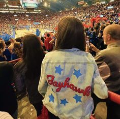 people are sitting in the stands at a basketball game and one person is wearing a jean jacket