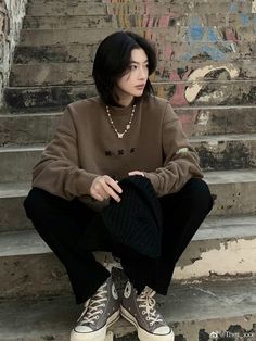 a woman sitting on the steps with her legs crossed and wearing converse shoes in front of some stairs