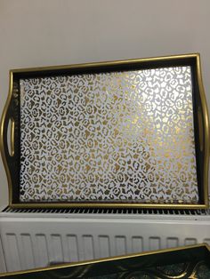 an ornate gold and white tray sitting on top of a radiator