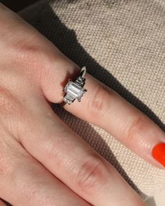 a woman's hand with an orange manicured nail polish and ring on it