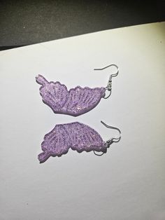 two pairs of purple lace earrings sitting on top of a piece of paper next to each other