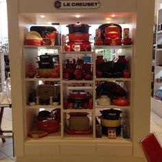 a display case filled with lots of different types of pots and pans on shelves