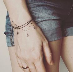 a woman's hand with a black and white tattoo on her left wrist,