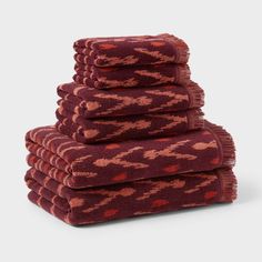 six towels stacked on top of each other in red and pink colors with an intricate pattern