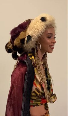 a woman with dreadlocks is walking down the street wearing a hat and scarf