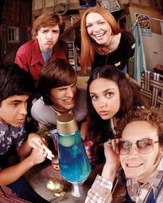 a group of people sitting around a table with a blue vase on top of it