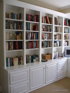 a living room filled with lots of white bookshelves