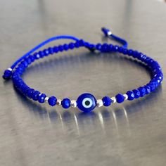 Adjustable Evil eye bracelet crafted by hand from 100% blue nylon string. Description: *3mm  Blue crystal *3, 2 and 1mm silver beads *Blue glass evil eye Size: Adjustable from 6" to 8" The bracelet opens by pulling the beads closest to the sliding knot in opposite directions and closes by pulling the small, dangling blue beads in opposite directions. Cheap Blue Evil Eye Bracelet For Friendship, Blue Evil Eye Bracelet, Blue Beaded Bracelets With Evil Eye, Blue Spiritual Friendship Bracelets With Sliding Knot, Blue Spiritual Friendship Bracelet With Sliding Knot, Blue Resizable Spiritual Friendship Bracelets, Resizable Blue Spiritual Friendship Bracelet, Adjustable Silver Beaded Bracelet With Evil Eye, Blue Beaded Spiritual Bracelets With Sliding Knot