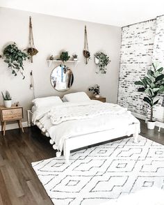 a white bed sitting in a bedroom on top of a hard wood floor next to a mirror