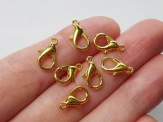 small gold plated charms in the shape of hats, umbrellas and boots on a person's hand