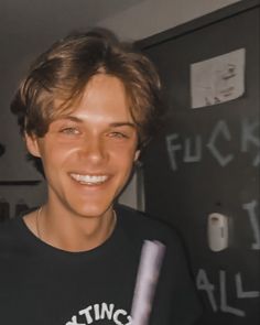 a smiling young man holding a baseball bat