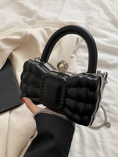 a woman's hand holding a black purse