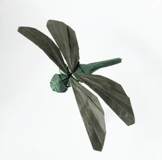 an origami bird flying in the sky with its wings folded back to look like leaves