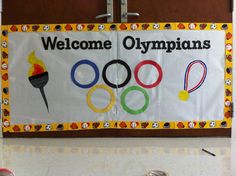 a welcome sign for the olympic games hanging on a wall