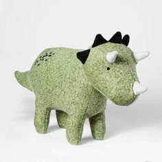 a green stuffed animal with black horns on it's head and nose, standing in front of a white background