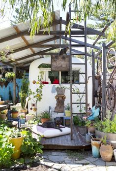 an outdoor garden with lots of potted plants and pots on the side of it