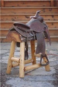 a horse saddle sitting on top of a wooden stool