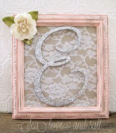 the letter g is made out of glitter and sits in a pink frame next to a flower