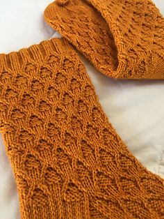 an orange knitted tie laying on top of a bed