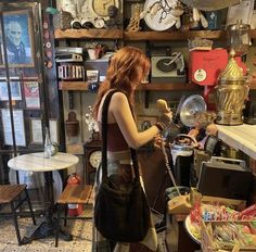 a woman standing in a room with lots of items