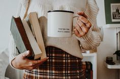 a woman holding a coffee mug and books