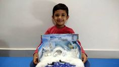 a young boy sitting on the floor holding a fake snowman and polar bear scene