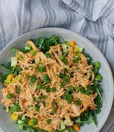 a white bowl filled with shredded chicken and veggies on top of a table