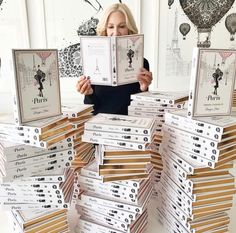 a woman is holding up some books in front of her face and looking at them