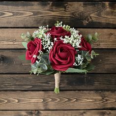 a bouquet of red roses and baby's breath sits on a wooden table top