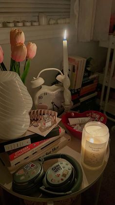 a table topped with candles and flowers next to a vase filled with tulips