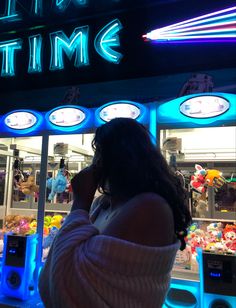 a woman standing in front of a neon sign that reads it's a time