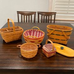 several baskets sitting on top of a wooden table next to plates and bowls with handles