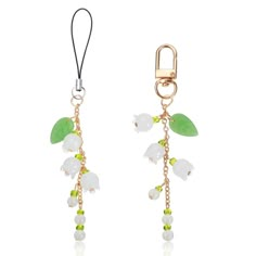 a pair of earrings with green leaves and white flowers hanging from the end of each ear