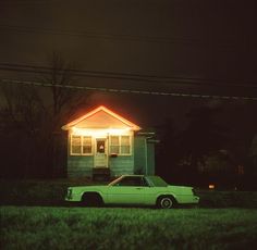 a car is parked in front of a house at night with the lights on,