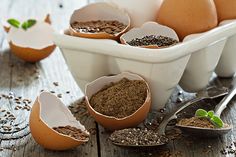 eggs and seeds in white bowls with spoons next to them on a wooden table